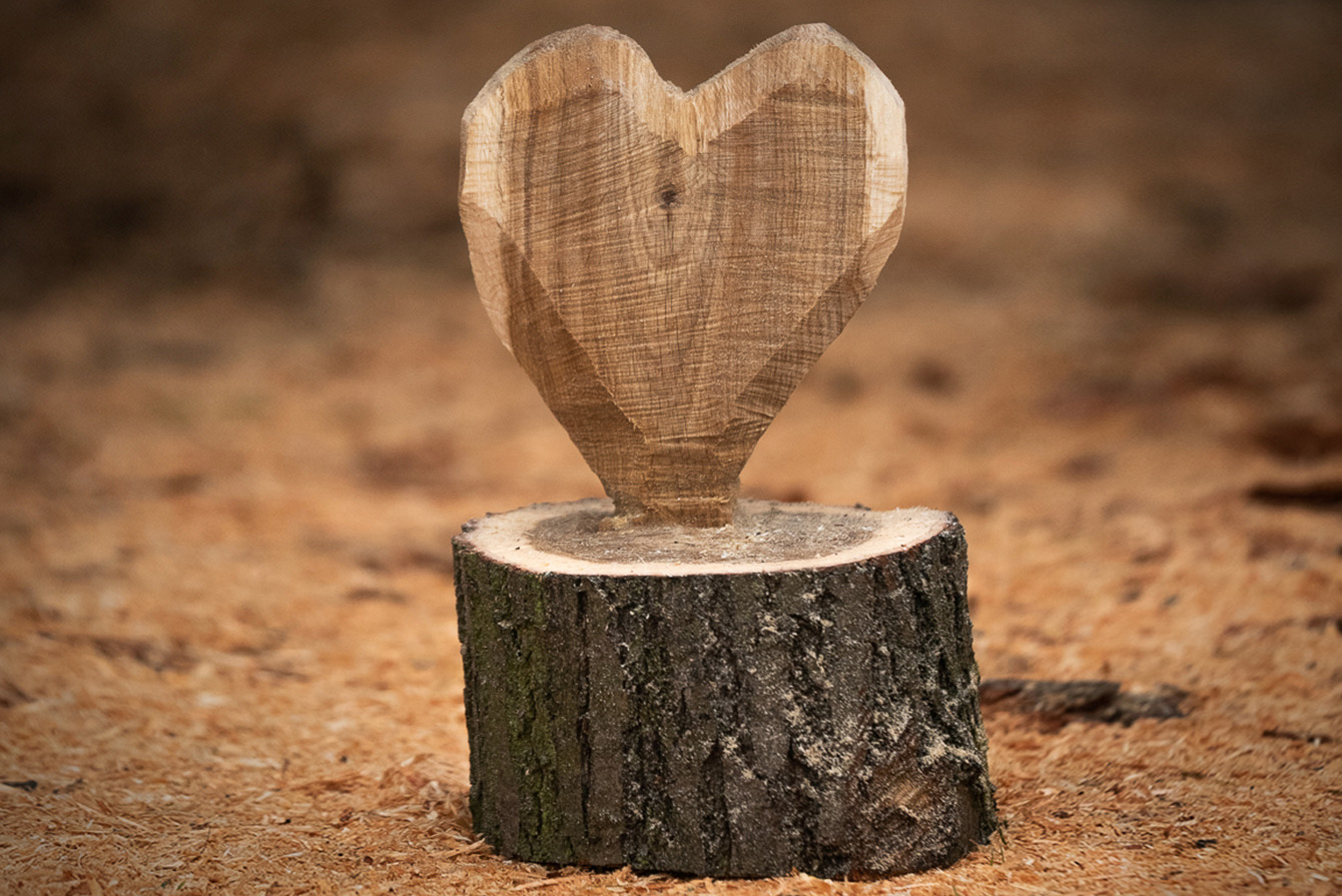 Un corazón decorativo de madera ya acabado con virutas alrededor.