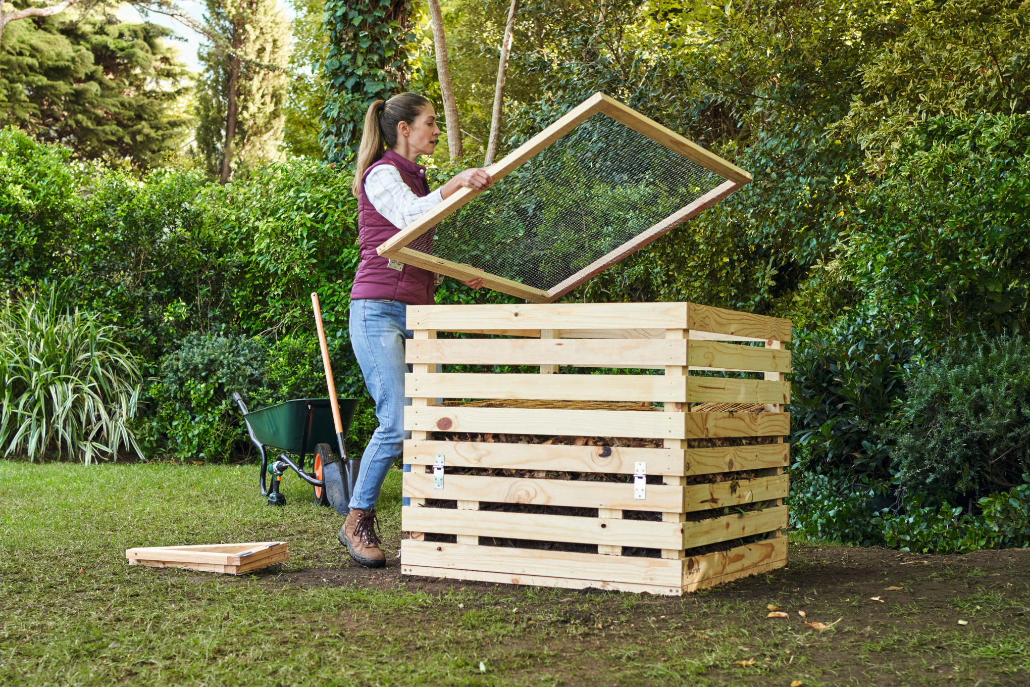 En un jardín, una mujer cubre un compostador de construcción propia