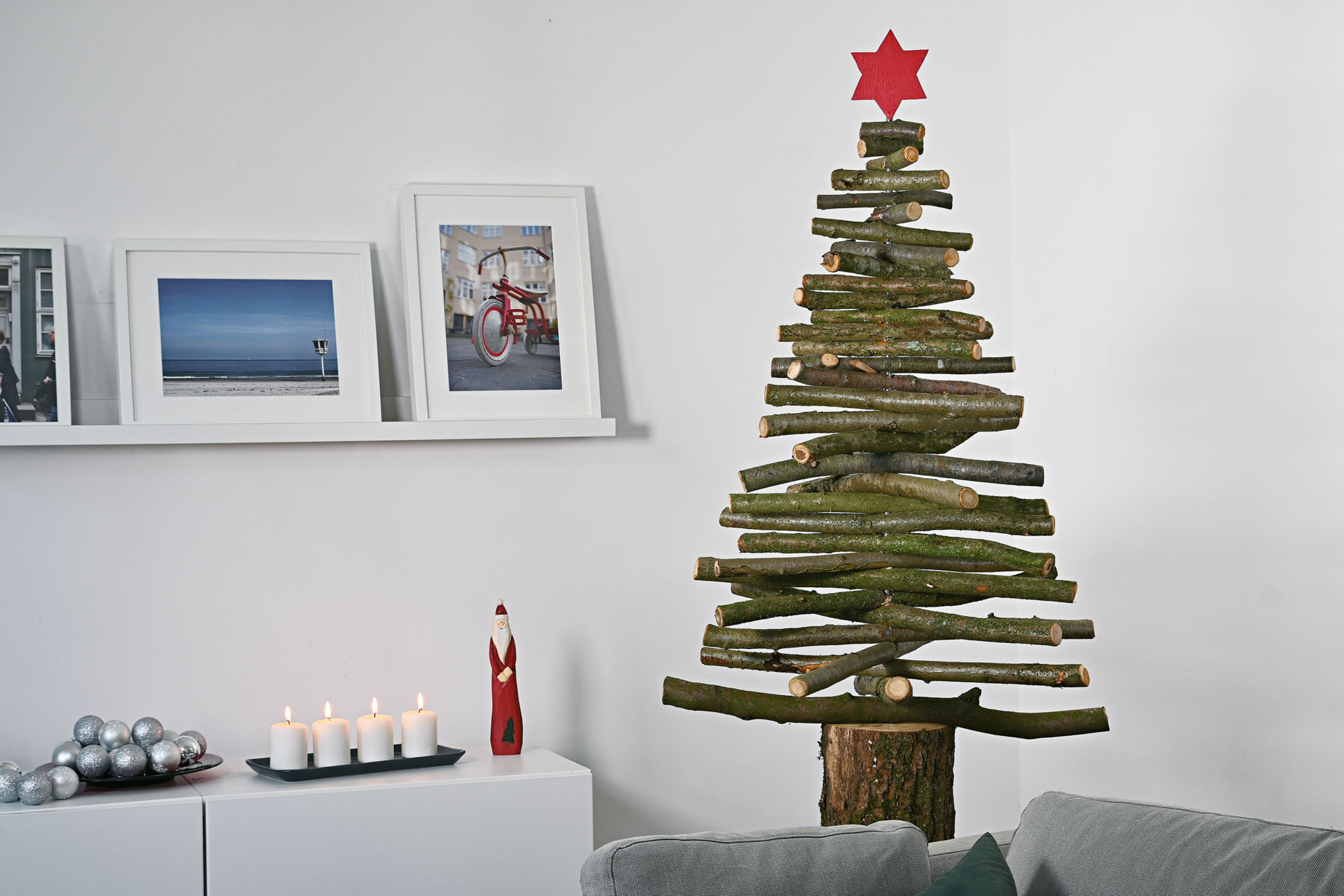 Árbol de Navidad casero de ramas de madera con una estrella roja en la punta en un interior con motivos navideños
