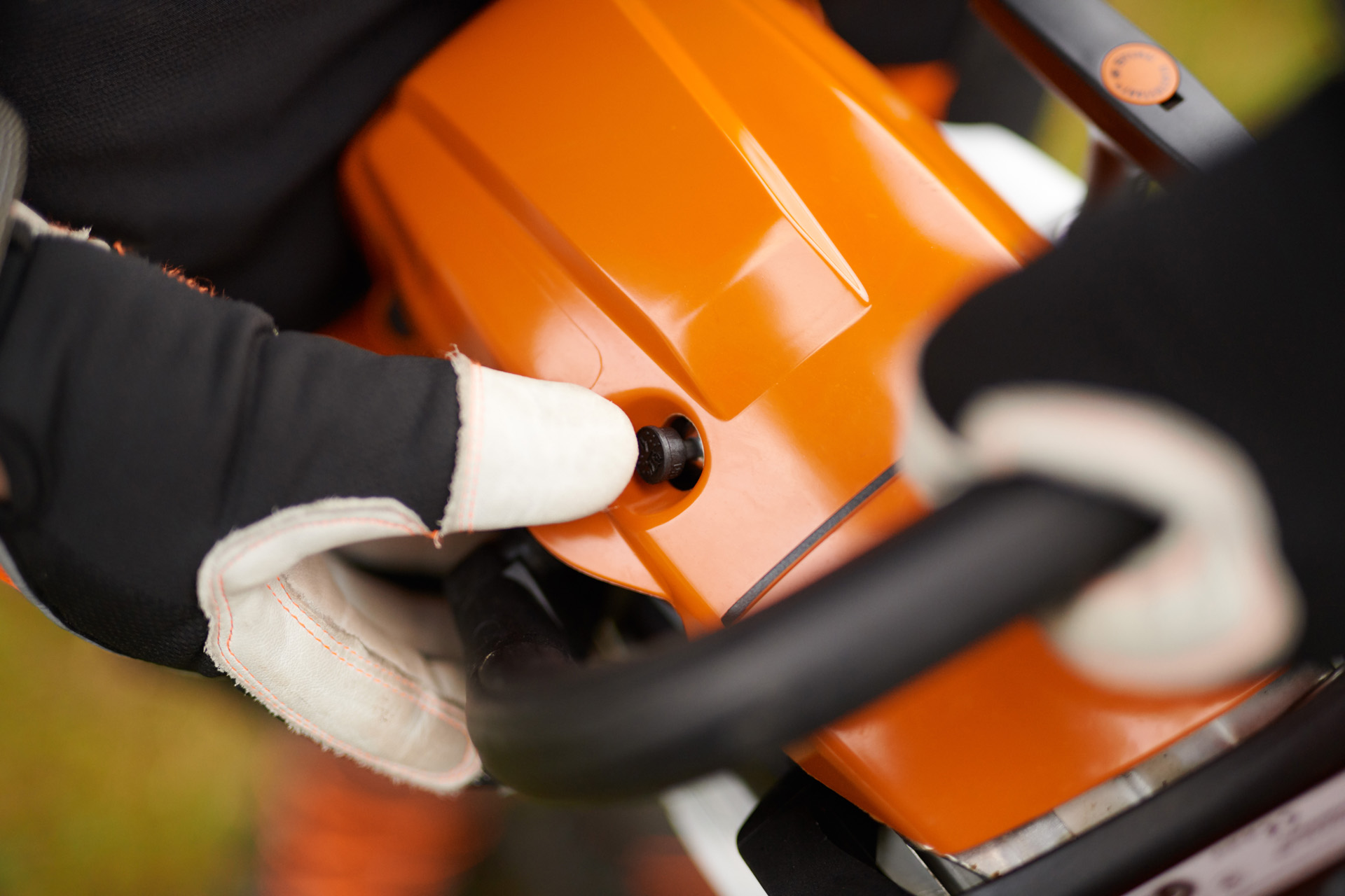 Un usuario con guantes acciona la válvula de descompresión de una motosierra de gasolina STIHL MS 261 C-M 
