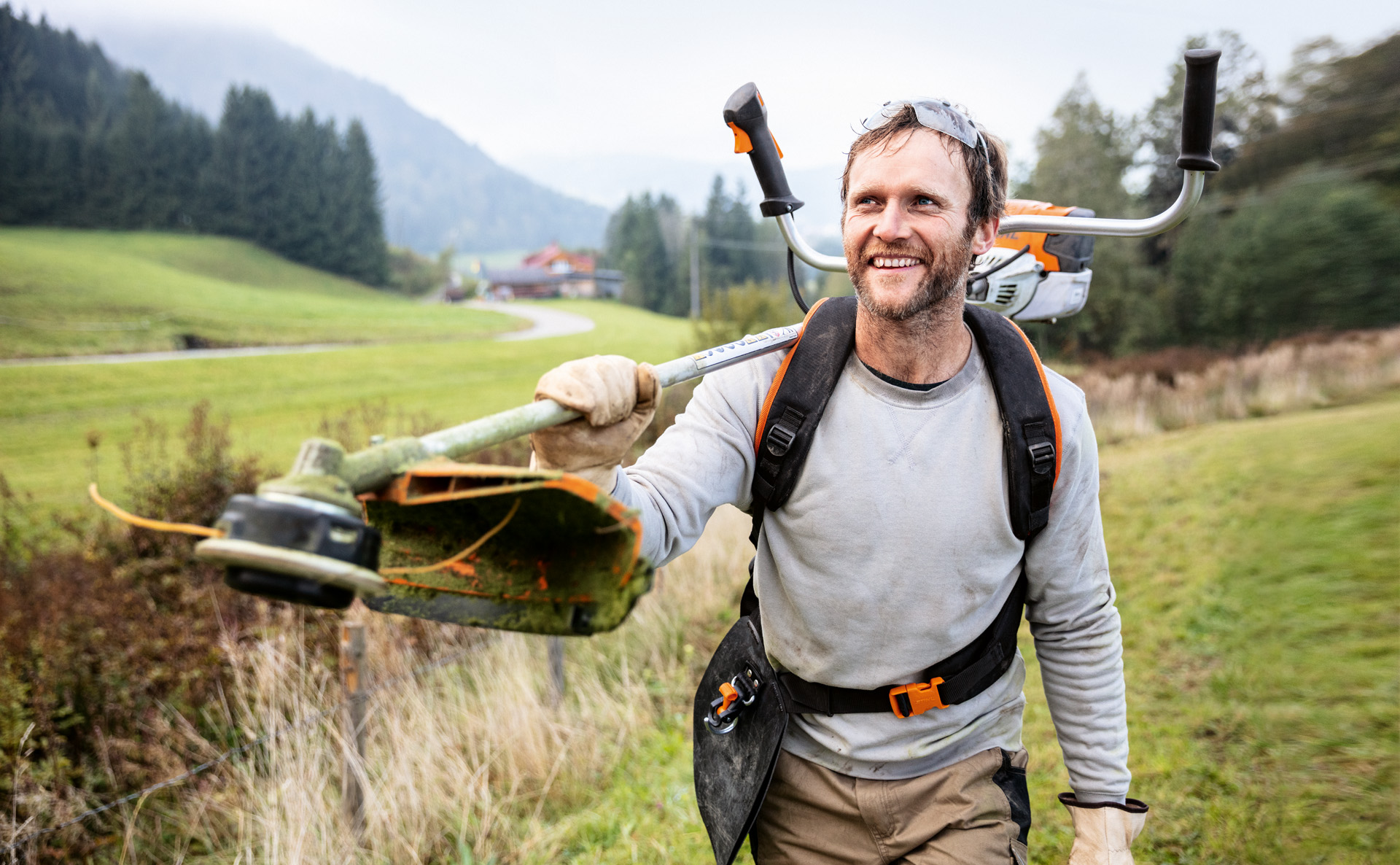 Un hombre sonriente con una desbrozadora STIHL FS 91 caminando por el campo