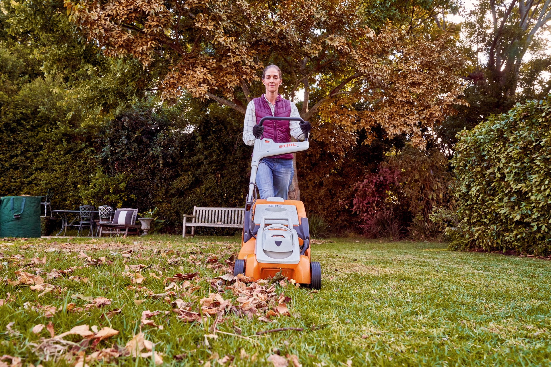 Una mujer se encarga del cuidado del césped en otoño con un cortacésped de batería STIHL RMA 339 C