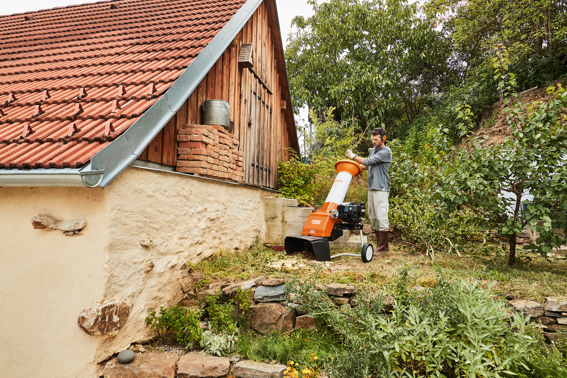 Un hombre utilizando una biotrituradora de gasolina STIHL GH 370 S en un terreno al lado de una casa