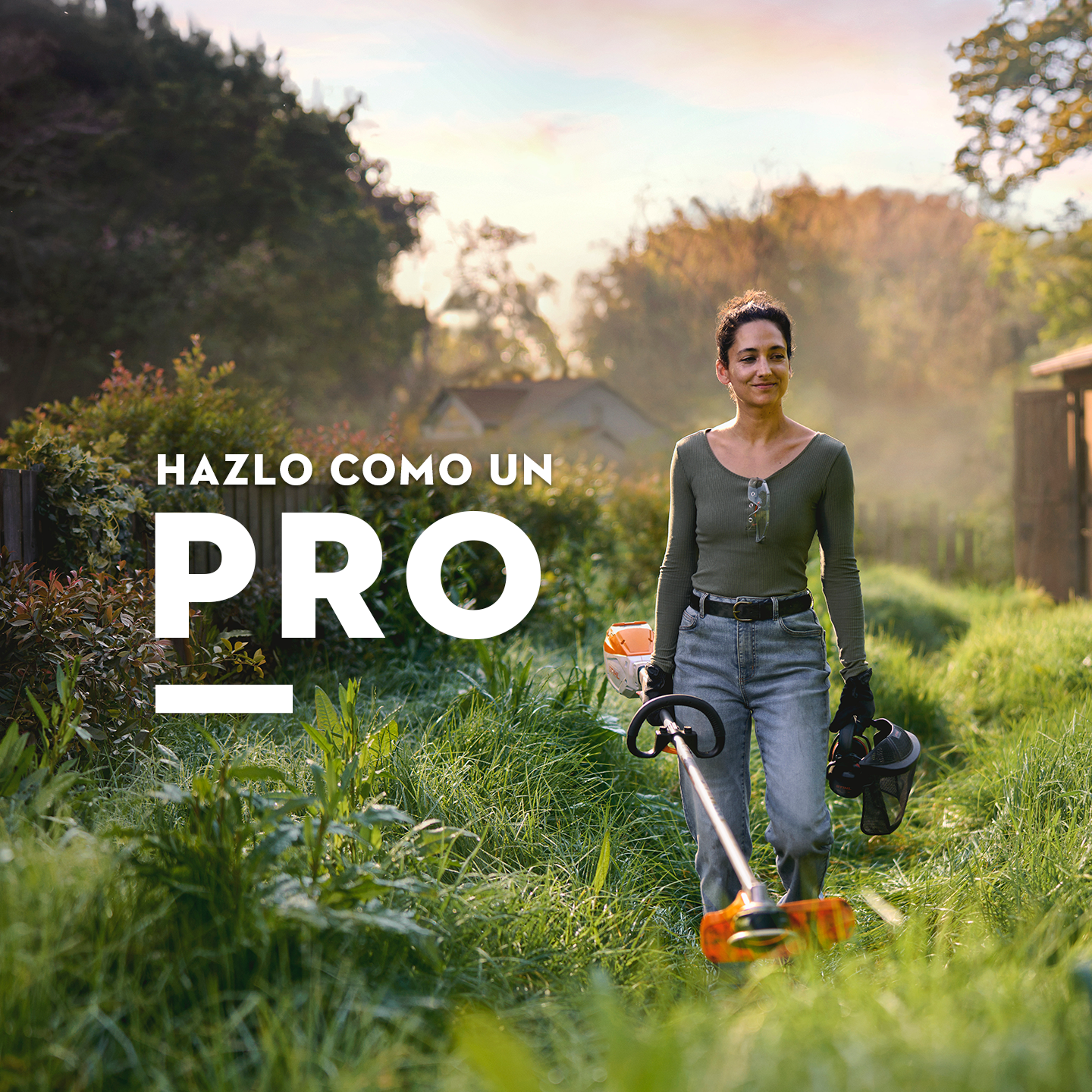 Una mujer sujetando una desbrozadora STIHL de batería mientras avanza entre la maleza