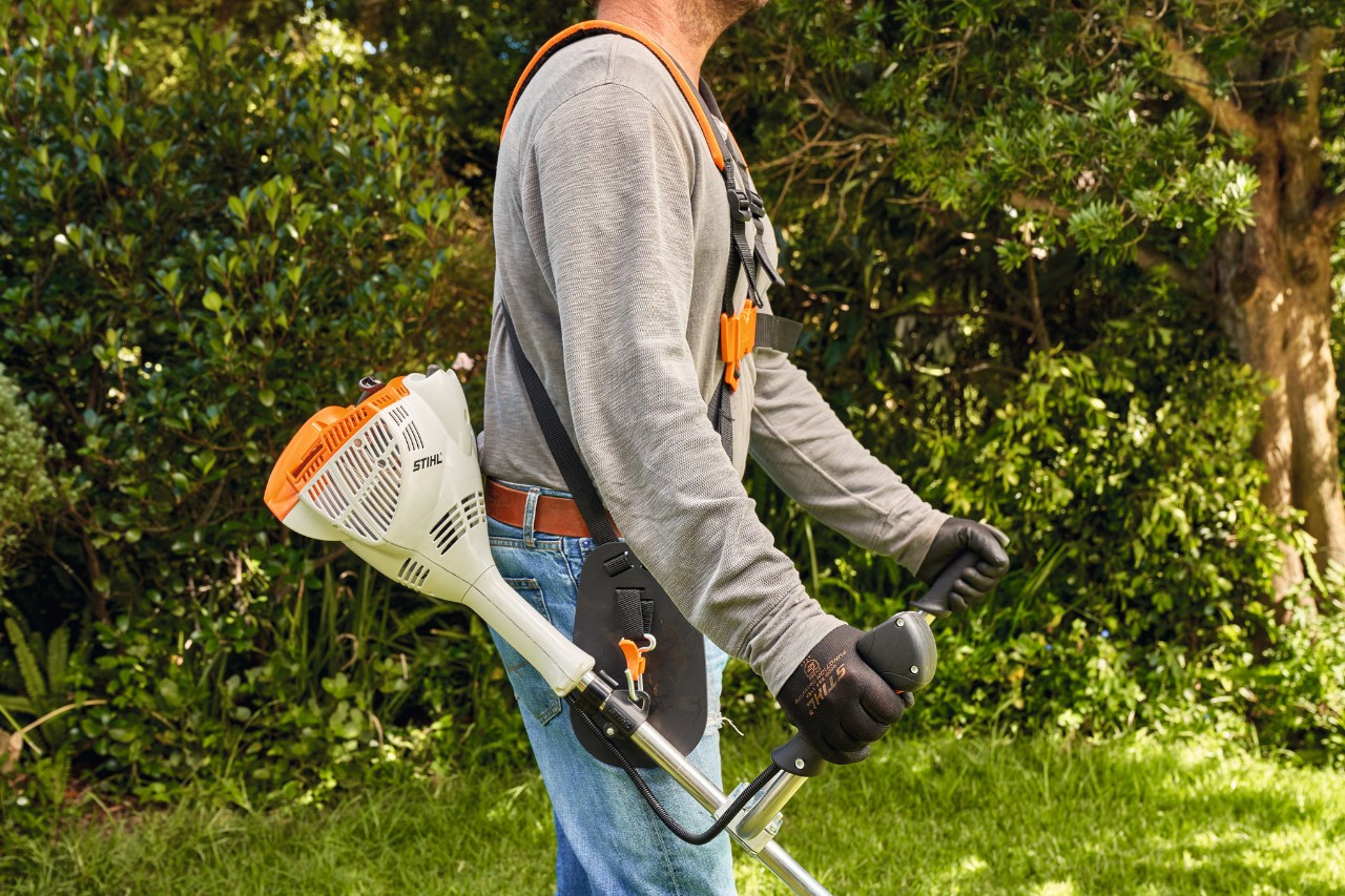 Un hombre levanta del suelo la desbrozadora de gasolina STIHL FS 56