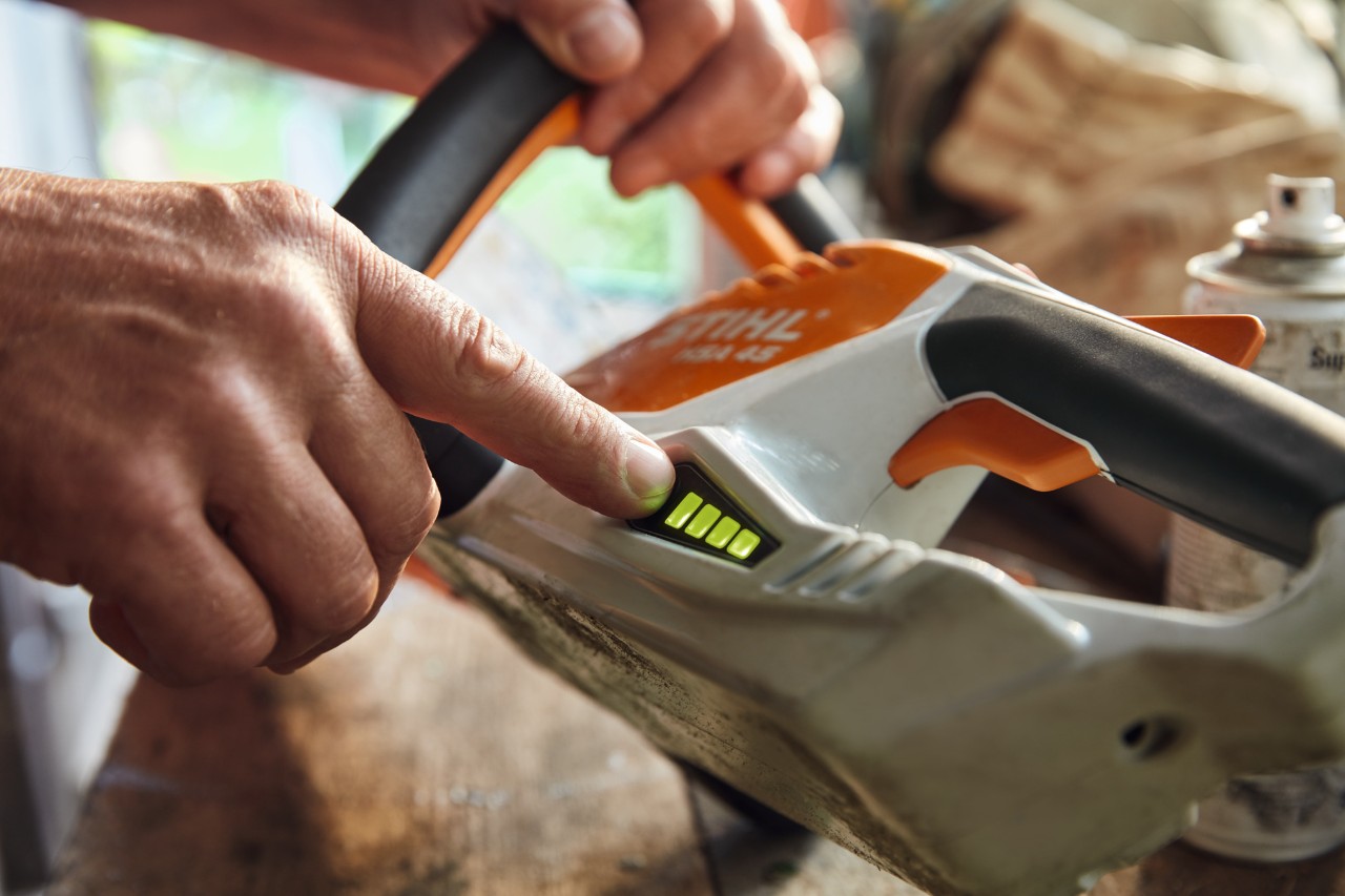 Una persona comprueba el nivel de carga de la podadora de setos inalámbrica STIHL HSA 45.