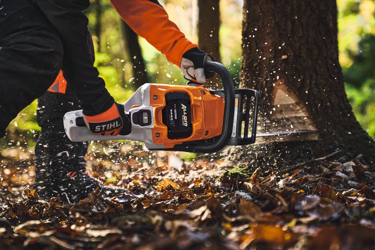 Un profesional de la madera tala árboles en el bosque con una motosierra a batería del modelo STIHL MSA260 y una batería ALLPRO.